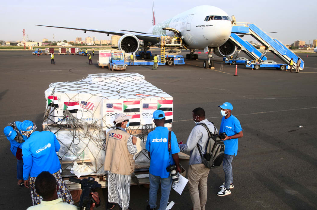 Aid workers check a shipment of vaccines against the coronavirus sent to Sudan by the Covax vaccine-sharing initiative, shortly after an Emirates plane landed at the airport in the capital Khartoum, on October 6, 2021.