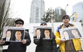 In this file photo taken on March 06, 2019 protesters hold photos of Canadians Michael Spavor and Michael Kovrig, who are being detained by China, outside British Columbia Supreme Court, in Vancouver.