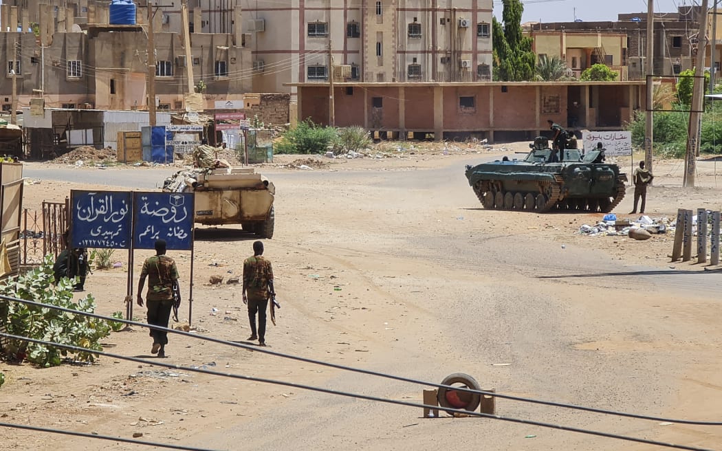 Sudanese Army sodliers walk near armoured vehicles stationed on a street in southern Khartoum, on May 6, 2023, amid ongoing fighting against the paramilitary Rapid Support Forces. - Air strikes battered Sudan's capital on May 6, as fighting entered a fourth week only hours before the warring parties are to meet in Saudi Arabia for their first direct talks. (Photo by AFP)