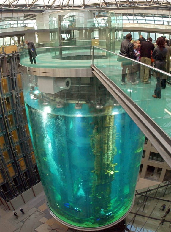 Visitors stand on the bridge leading to the 'Aquadome' inside the lobby of the future Radisson SAS Hotel in Berlin, 1 December 2003. The Aquadome is 25 metres high and has a diameter of 12 metres. Inside the tank is an elevator which offers a panoramic view of colourful shoals.