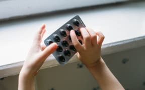 Child takes pack of pills. Dangerous situation.
