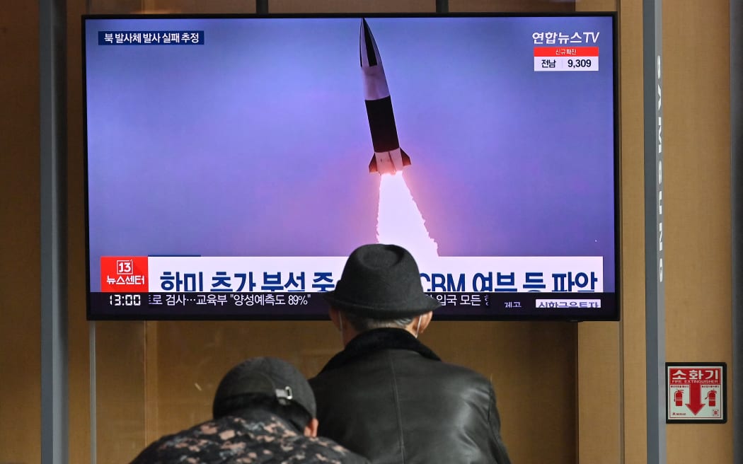 People watch a television screen showing a news broadcast with file footage of a North Korean missile test, at a railway station in Seoul on March 16, 2022.
