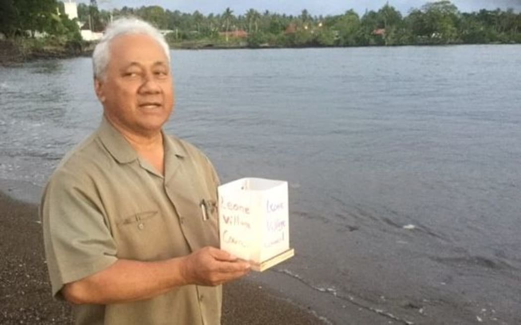 Senator Faiivae Alex Godinet prepares to place a floating candle in the sea