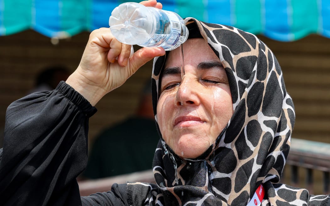 Çıkış yapan bir Türk Müslüman hacı, 20 Haziran 2024'te Suudi Arabistan'ın kutsal şehri Mekke'de beklerken serinlemek için başının üzerinden bir şişeden soğuk su döküyor. (Fotoğraf: Abdul Ghani Bashir/AFP)