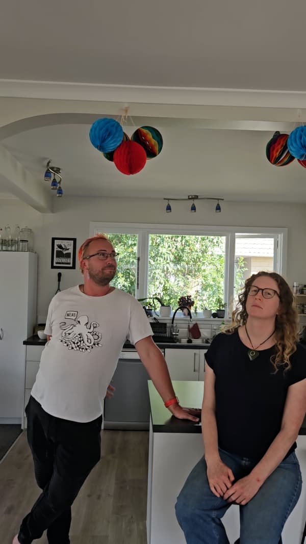 Two friends, a man and a woman stand in front of their kitchen bar, looking around and enjoying the fact that they are now co-owners of their own home.