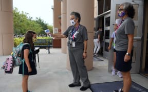 Staff checking the temperature of students in Orlando, Florida, last year. The upcoming reopening of schools is causing fierce debate.