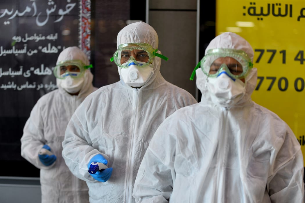 A medical team wearing protective outfit awaits to check Iraqi passengers returning from Iran upon their arrival at the Najaf International Airport on February 21, 2020.