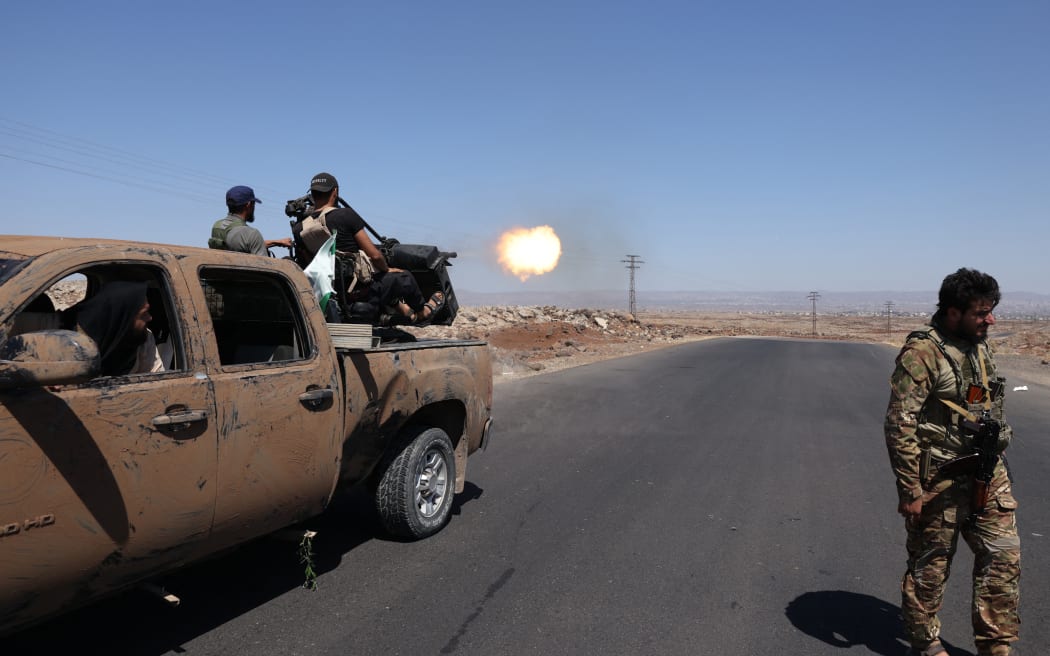 Syrian security forces fire towards a position near the Mazraa area, near Sweida on July 14, 2025, following clashes between Bedouin tribes and local fighters in the predominantly Druze city. At least 89 people were killed in the southern Syrian province of Sweida as clashes between Sunni Bedouin tribes and Druze fighters raged for a second day on July 14, 2025, a monitor said. (Photo by Bakr ALkasem / AFP)