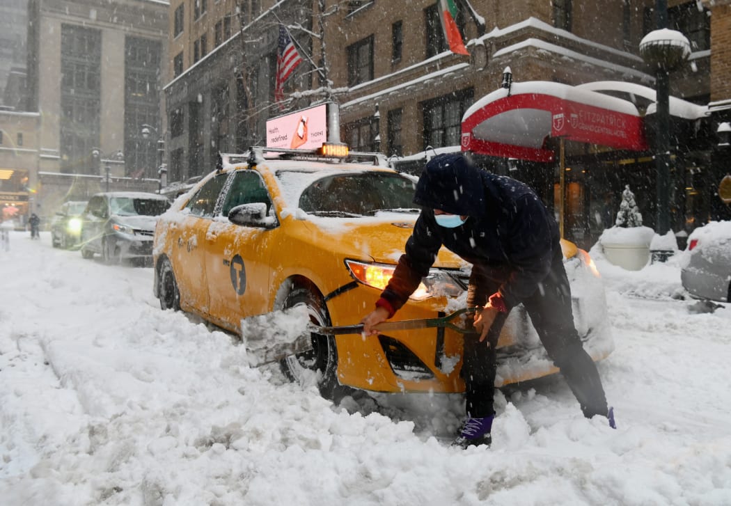 A taxi cab driver shovels through heavy snow during a winter storm on 2 February, in New York City.