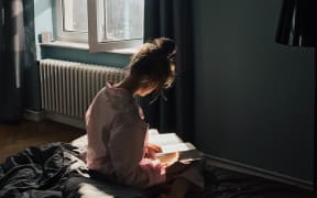 Young woman reading on a bed