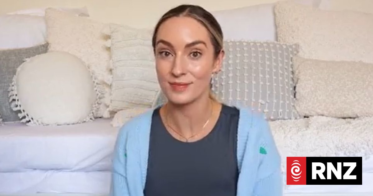 A woman in a light blue cardigan sitting on a sofa.