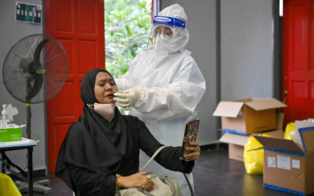 This picture taken on May 27, 2021 shows a woman taking a selfie as she receives a test from a medical worker at a free Covid-19 coronavirus testing site in Shah Alam, on the outskirts of Kuala Lumpur, Malaysia.