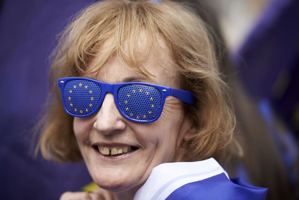 A pro-EU demonstrator waves a Union flag whilst wearing European Union flag-themed attire during an anti-Brexit protest.