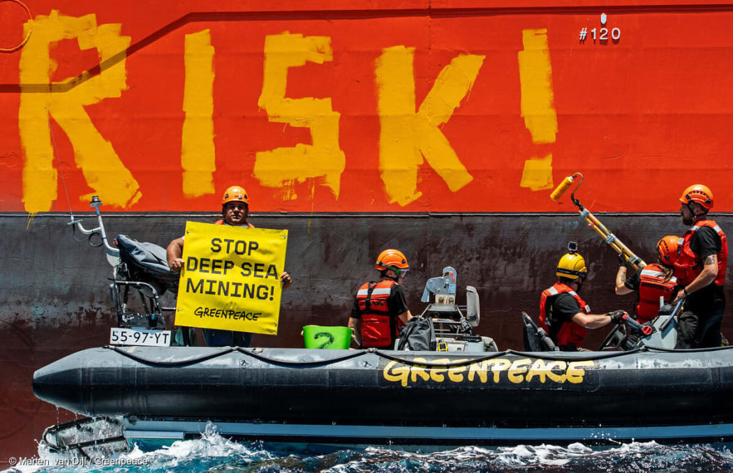 Greenpeace International activists paint the word 'RISK!' on the starboard side of Normand Energy, a vessel chartered by the Belgian company Global Sea Mineral Resources (GSR).