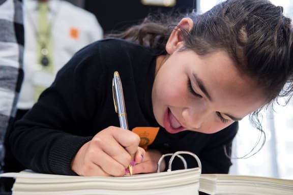 Te Hokairangi Olsen-Miller (8) signs the Ahuriri deed of settlement.