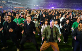American TV host and comedian Conan O'Brien (centre) does the haka with Kiwi director Taika Waititi (right) and thousands of people at Eden Park for the world record on 29 September, 2024.