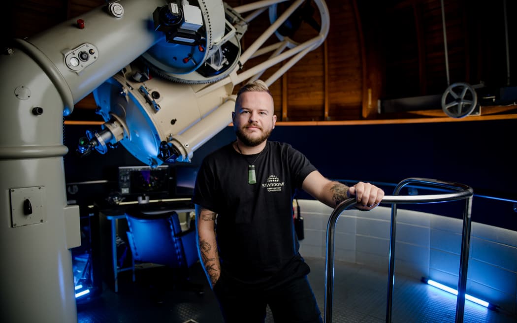 Astronomy educator Josh Aoraki stands to the right a Stardome telescope.