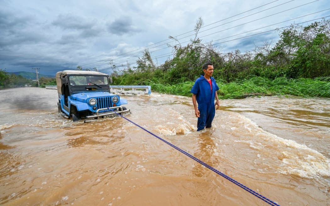 A driver tries to remove his vehicle from a flooded area after heavy rains caused by Hurricane Melissa in the town of San Miguel de Parada, Santiago de Cuba province, on October 29, 2025.