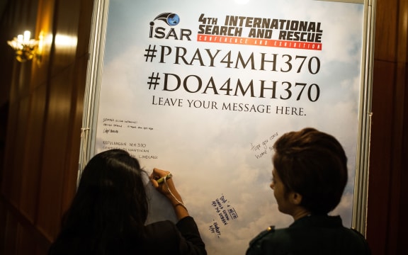 A visitor adds a message for missing passengers at an International Search and Rescue Conference and Exhibition in Kuala Lumpur on Tuesday.