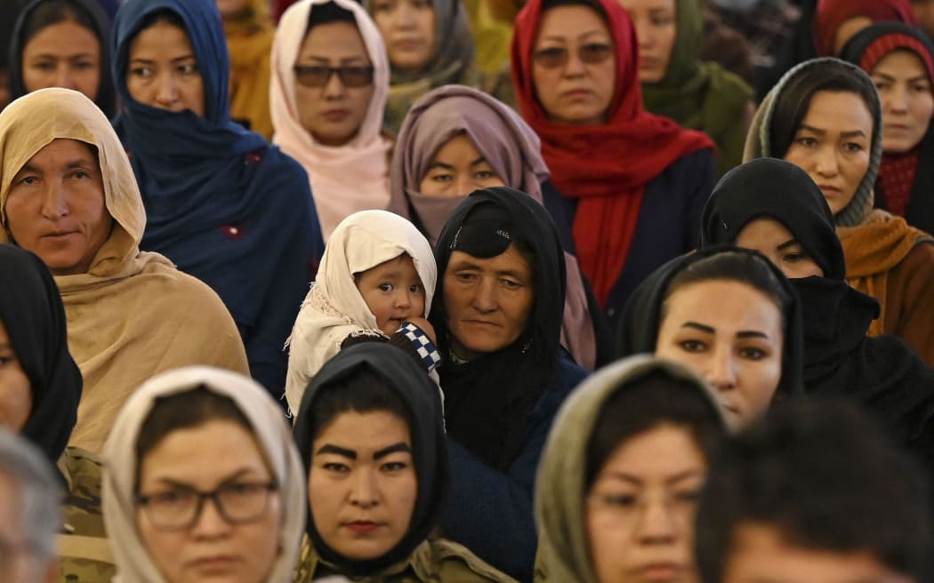 A Hazara woman (C) holds her child as she with others attend an event on International Women's Day in Bamiyan Province on March 8, 2021.