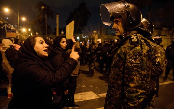 A woman attending a candlelight vigil, in memory of the victims of Ukraine International Airlines Boeing 737, talks to a policeman following the gathering in front of the Amirkabir University in the Iranian capital Tehran on January 11, 2020.