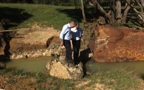 Primary Industries Minister Nathan Guy, left, and Hunua MP Andrew Bayly assess flood damage on a farm in rural Auckland.