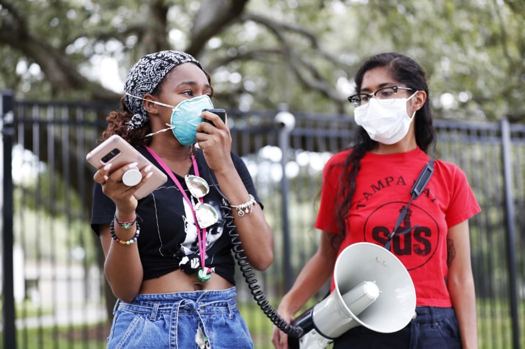 TAMPA, FL - JULY 02: University of South Florida students Makyla Burks, (L) and Eithne Silva both wear face masks while protesting in front of the Lifsey residence where the USF President Steven Currall lives on campus on July 2, 2020 in Tampa, Florida. T
