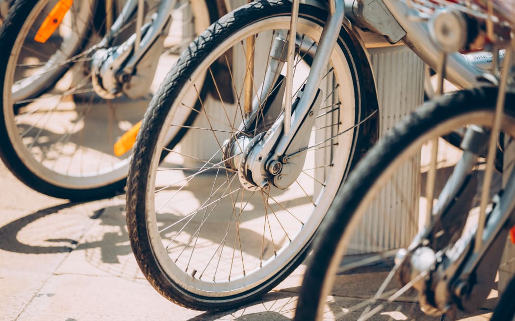 Row Of Parked Bicycles Bikes For Rent On Sidewalk. Close Up Of Wheel