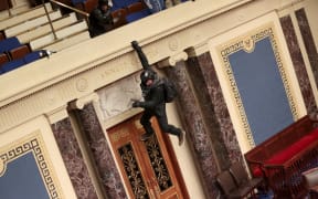 A protester is seen hanging from the balcony in the Senate Chamber on January 06, 2021 in Washington, DC.