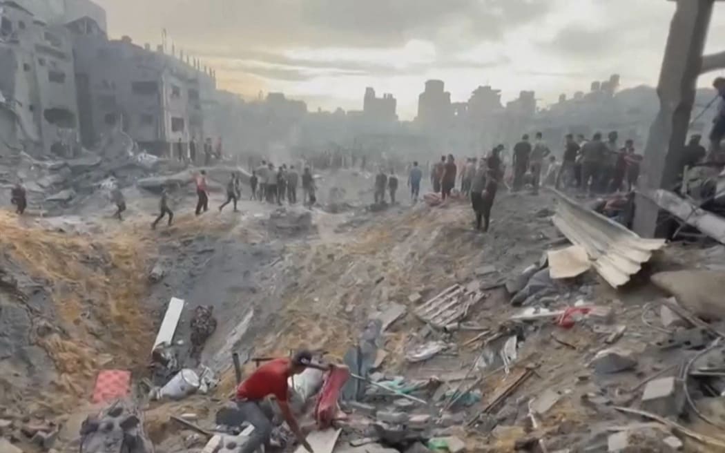 This image grab taken from AFPTV video footage shows Palestinians looking for survivors in a crater following a strike on a refugee camp in Jabalia on the northern Gaza Strip, on 31 October, 2023, amid relentless Israeli bombardment of the Palestinian territory.