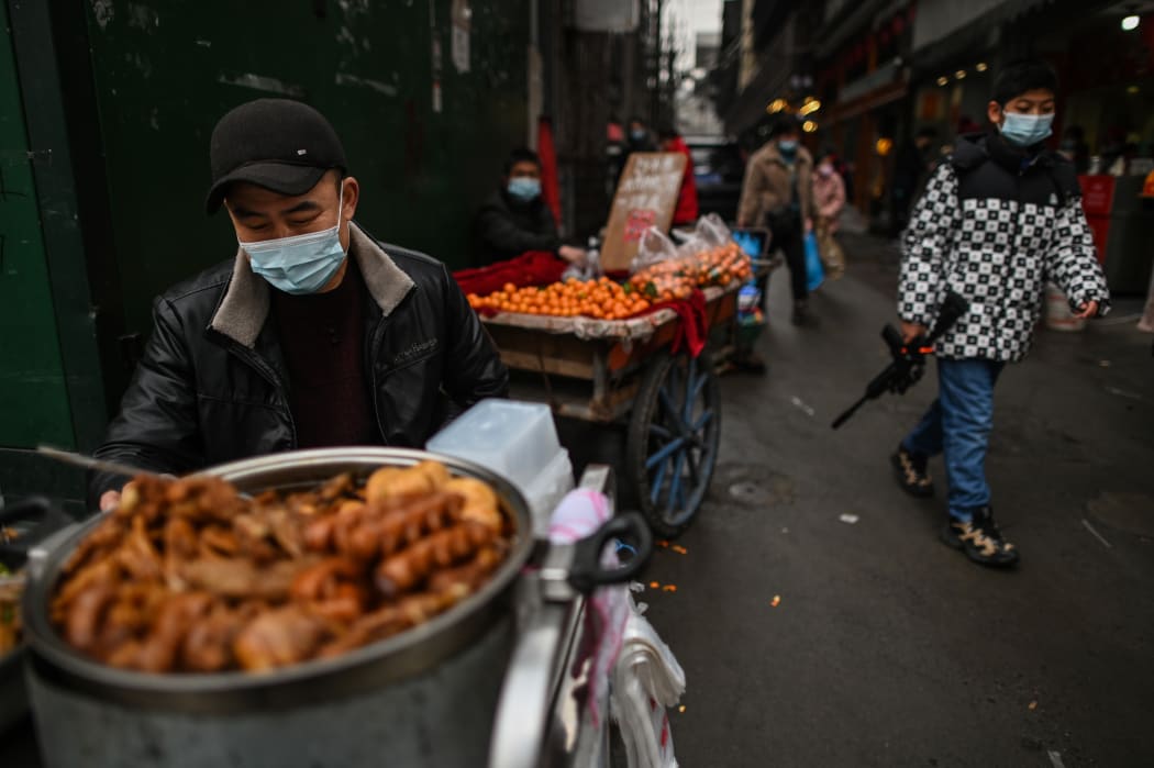 A man wearing a face mask sells food in an alley in Wuhan, China.