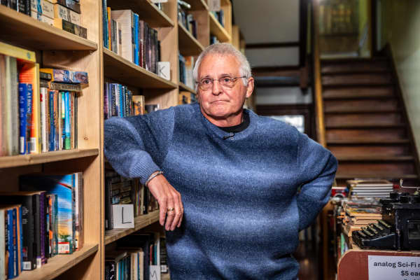 Hard To Find Books store owner Warwick Jordan leans with one arm on a shelf of books at his Eden Terrace shop.