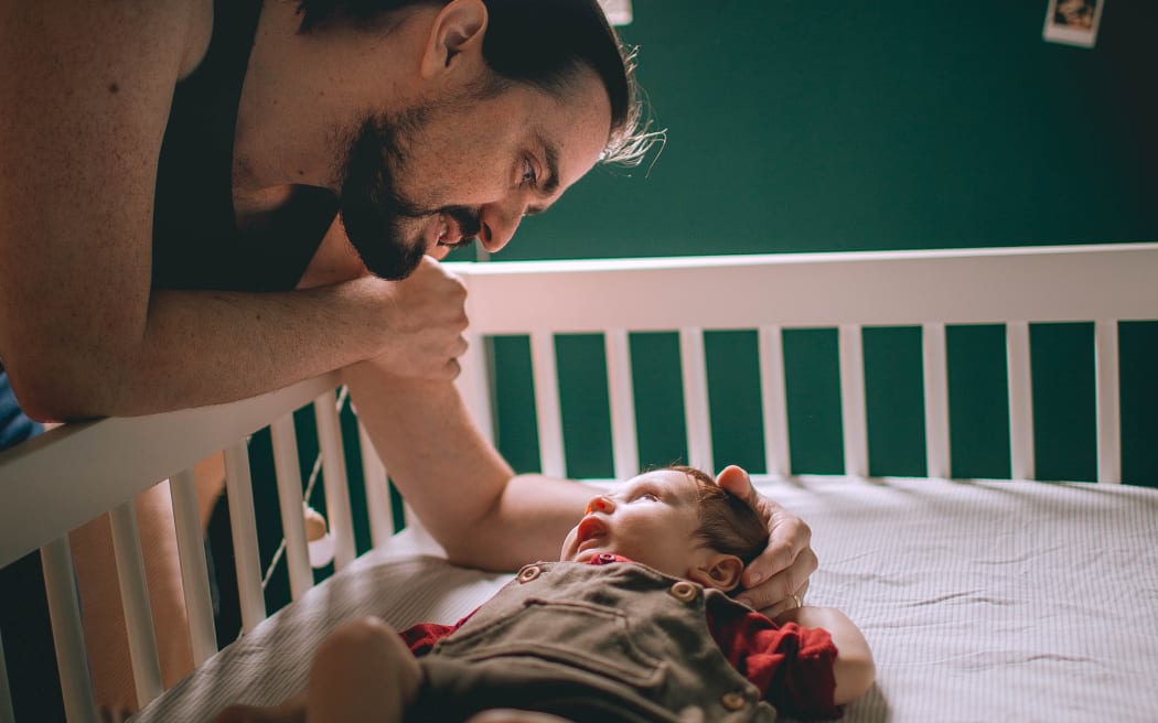 father and baby in cot