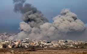 This picture taken from the Israeli side of the border with the Gaza Strip shows smoke plumes rising from explosions above destroyed buildings in the northern Gaza Strip on January 13, 2025 amid the ongoing war between Israel and Hamas. (Photo by Menahem KAHANA / AFP)