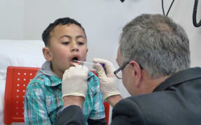 Soloiautele (AJ) Taliulu being throat-swabbed by Dr Bryan Betty.