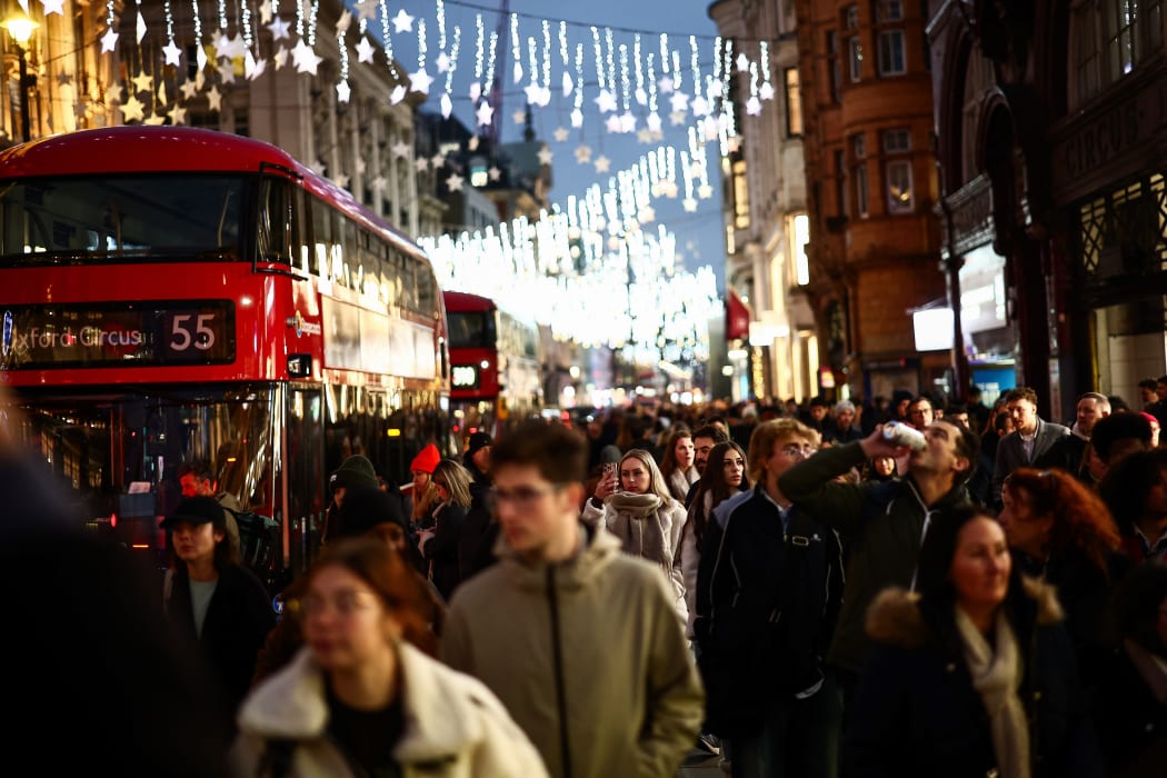 Shoppers walk under neath the Christmas lights on Oxford Street, in central London, on December 13, 2024. (Photo by HENRY NICHOLLS / AFP)