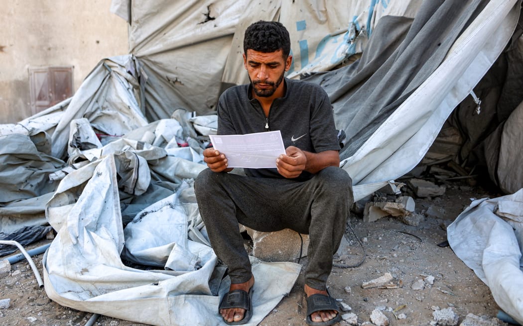 A man reads one of the leaflets dropped by the Israeli military on Gaza City, urging evacuation south to al-Mawasi.