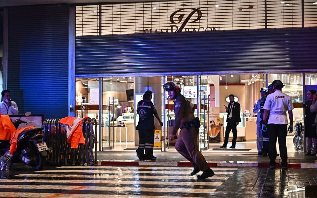 Police officers and rescue workers stand outside Siam Paragon shopping centre in Bangkok on October 3, 2023, following a shooting in the mall.