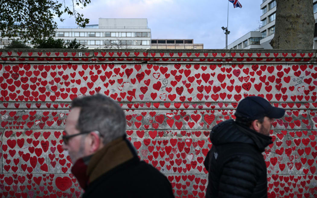 People walk past the National Covid Memorial Wall, dedicated to those lost in the United Kingdom from Covid, in central London on November 20, 2025, ahead of the publication of a new report on government decision-making during the pandemic. The UK's Covid-19 lockdowns were "too little, too late" and could have been avoided if restrictions were put in place sooner, an inquiry into the country's response to the global health emergency concluded on November 20. (Photo by Chris J Ratcliffe / AFP)