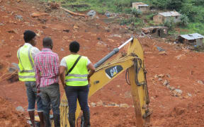 Residents watch the rescue operations at the side of a mud slide in the Sierra Leone capital Freetown on 15 August, 2017.