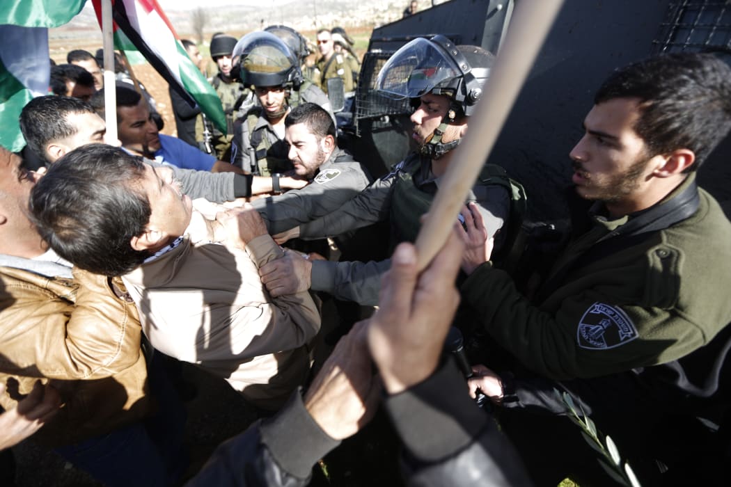 An Israeli border guard grabs Palestinian official Ziad Abu Ein (L) during a demonstration in the village of Turmus Aya near Ramallah, on 10 December 2014.