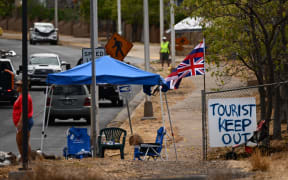 The Flag of Hawaii waves by a sign reading "Tourist Keep Out" in the aftermath of the Maui wildfires in Lahaina, Hawaii.