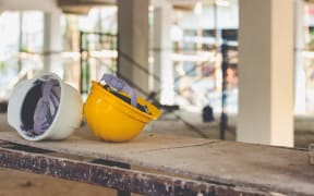 Yellow and white helmets are placed on the wooden table inside the construction area.