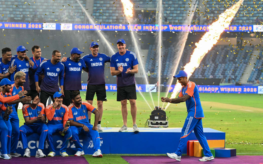 India's captain Suryakumar Yadav (R) playfully pretends to hold the Asia Cup trophy after his team refused to accept it after beating Pakistan in the Asia Cup T20 final in Dubai, September 28, 2025. (Photo by Sajjad HUSSAIN / AFP)