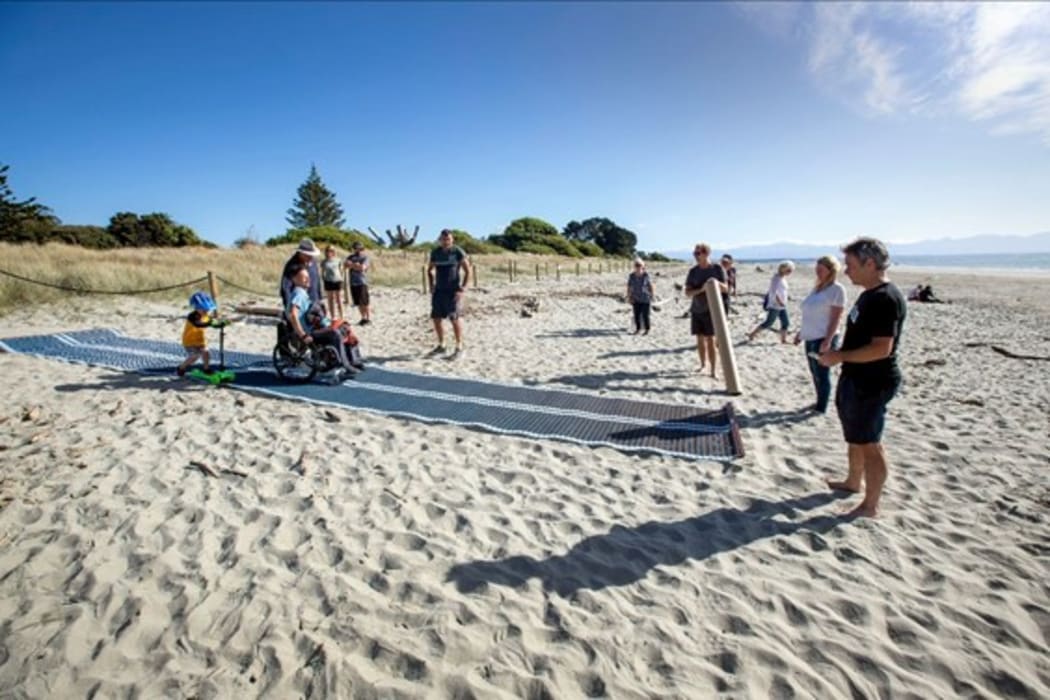Caleb Harcus and his son, Ethan, trialled a new Mobi-Mat at Tāhunanui on Monday, a device that allows wheelchair users and those with strollers and walkers, who struggle to get over soft sand, to get closer to the water.