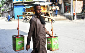 A man carries water containers as he walks along a street in Muzaffarabad, the capital of Pakistan-administered Kashmir.