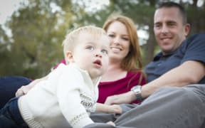 11396063 - cute child boy looks up to the sky as young parents smile.