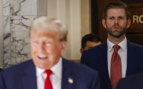 Former US President Donald Trump speaks to the media as his son Eric Trump looks on during the third day of his civil fraud trial in New York on 4 October 2023.