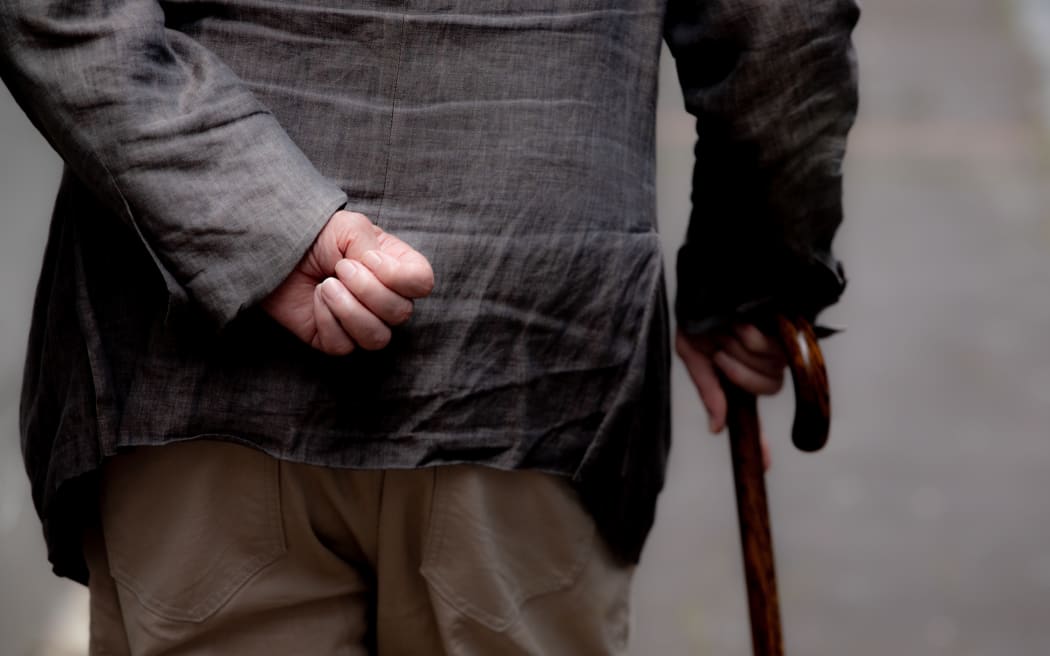 Elderly man walks on a street in Auckland.