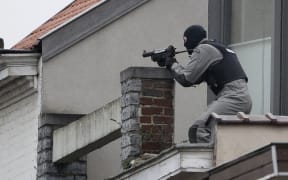 A member of the special forces takes position on a roof near the site of a shooting in the southern Forest district of Brussels on March 15, 2016.